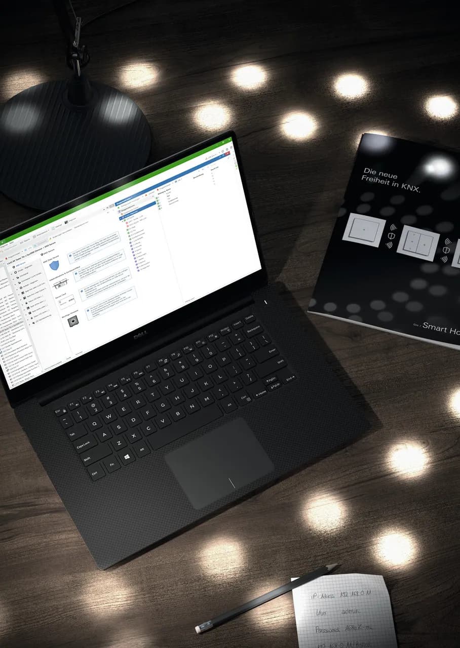 KNX-Programmierung mit der ETS6-Software auf einem Laptop, daneben Gira Smart Home Unterlagen